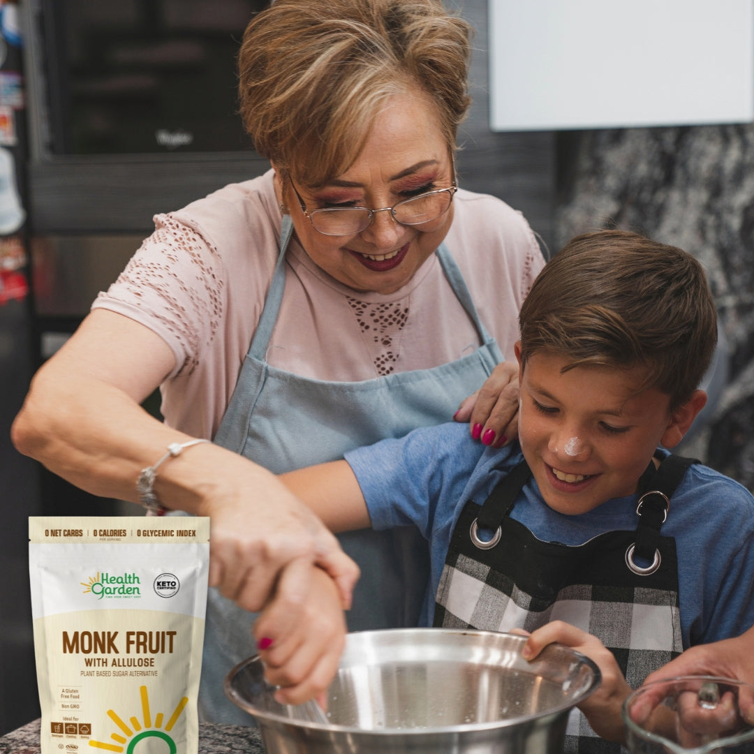 Woman and child in aprons mixing ingredients in a bowl with Health Garden Monk Fruit packaging nearby.